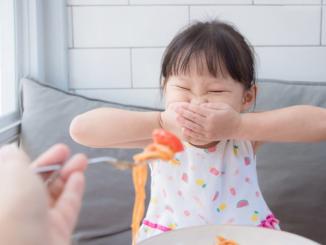Little asian girl refuse toeat tomato in spagethi from her mother